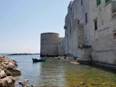 Sulla destra, a picco sulle onde, svetta il possente Torrione Passari, fortificazione circolare che "consolidava" il sistema di torri costiere di avvistamento spagnole del 500